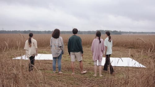 A Guy and Two Young Girls Barefoot Leave the Row and Stand on Platforms in a Wheat Field for a