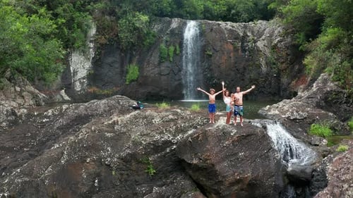 Family Near a Waterfall in the Tropics