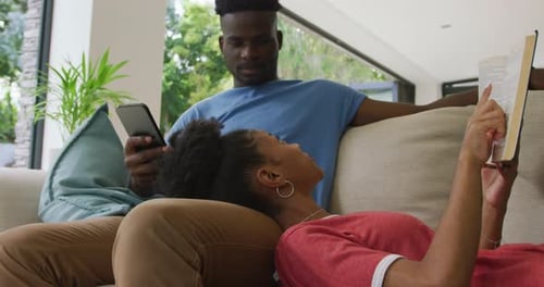 Couple Relaxing at Home with Book and Smartphone