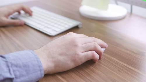 Top View of a Young Man's Hands Working with Computer Keyboard and Mouse