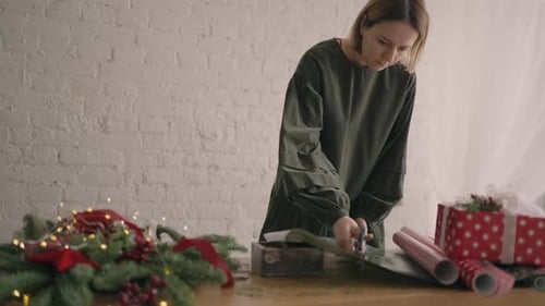 Woman Cutting Wrapping Paper at Christmas Celebration