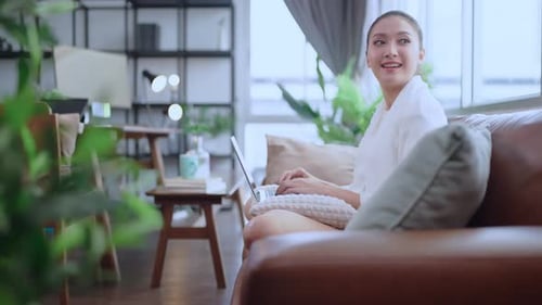 Woman Working on Laptop at Home on Sofa