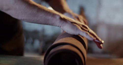 Hands Unrolling Brown Leather Material on Table