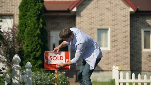 Proud Man Changing for Sale to Sold Signboard in Front of House, Buy New Home