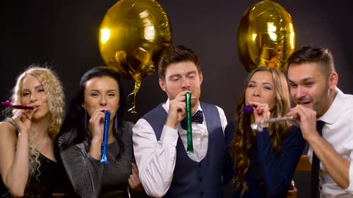Group Celebrate Birthday Party With Horns and Balloons