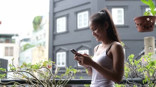 Smiling Woman Using Mobile Phone on Balcony