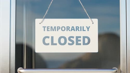Temporarily closed due to COVID-19. Zoom in white close sign on the glass door.
