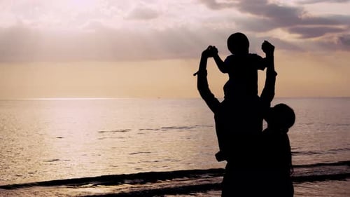 Happy asian family looking sunset on the beach in vacation together in evening.