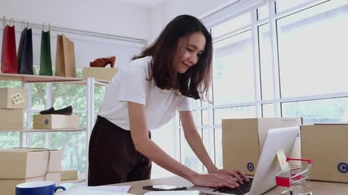 Woman Using Laptop for Online Business and Shipping