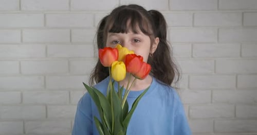 Smiling Girl Holds Bouquet of Colorful Tulips