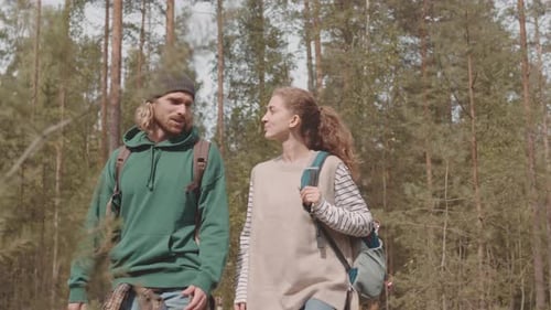 Couple with Backpacks Walking in Forest