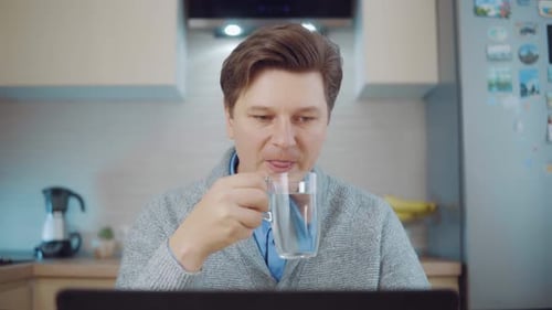 Man Hydrating While Working on Laptop At Home