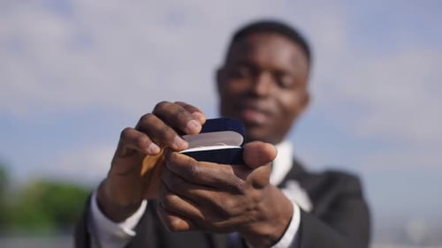Groom Shows Wedding Rings Outside