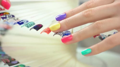Woman Examines Nail Designs with Colorful Manicure