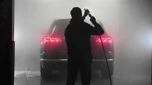 Worker Cleaning Automobile with High Pressure Water Jet at Car Wash