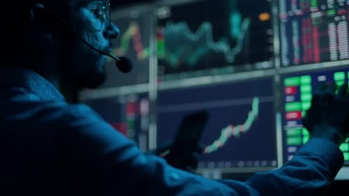 Der Händler arbeitet mit mehreren Computerbildschirmen mit Diagrammen und Datenanalysen sowie einem Börsenmakler