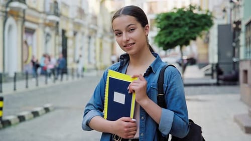 Outdoor Portrait of Smiling Teenage Female Student Looking at Camera in City