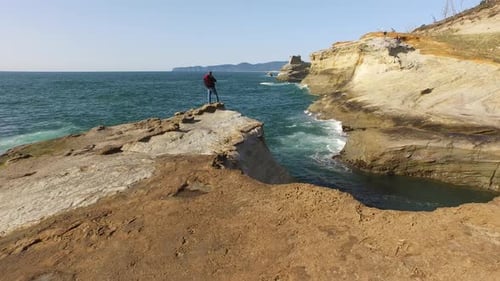 Aerial shot of backpacker standing on rock overlooking Pacific Ocean
