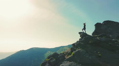A Man Standing on Top of a Mountain with and Raising His Hands Up the Mountain