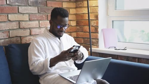 Man Using Laptop and Phone at Home