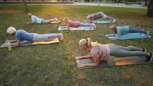 Yoga Teacher and Senior People Practicing Cobra Pose in Park