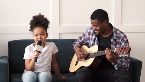 Girl Singing as Man Plays Guitar at Home