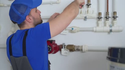 Man Repairing Plumbing Pipes in Indoor Setting