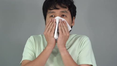 Man Blowing His Nose with a Tissue
