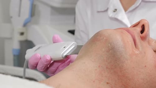 Man receiving facial cleaning at cosmetology clinic