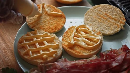 Burger Buns Being Decorated with Sauce