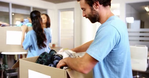 Male Volunteer Packing Clothes in Donation Box