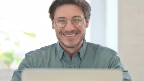 Smiling Man Wearing Glasses Using Laptop