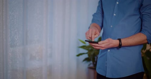 Man Using Smartphone Indoors with Blue Shirt