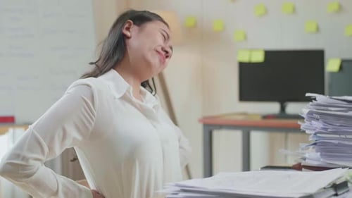 Close Up Of Asian Woman Having Backache While Working Hard With Documents At The Office