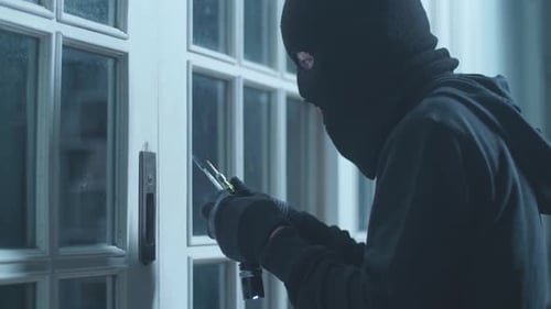 Close Up Of Thief Man Holding Flashlight Looking Inside The House Before Trying To Open The Door