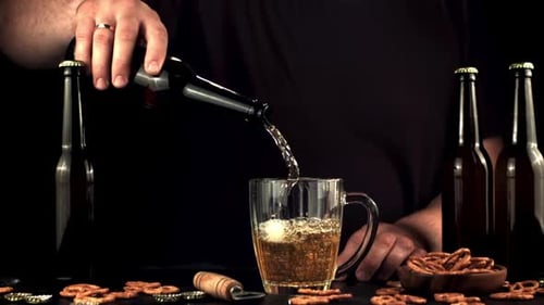 Pouring Cold Beer into Mug with Pretzels