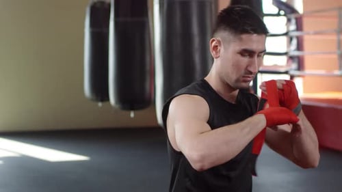 Young Adult Male Puts On Boxing Hand Wraps