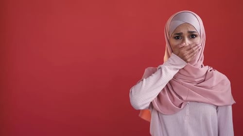 Worried Woman Covers Mouth in Modest Clothing