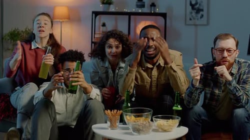 Slow Motion of Friends Watching Sports Game on TV Expressing Disappointment Indoors in Dark