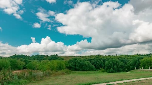 Sommerlandschaft des Parks mit grünen Bäumen und blauem bewölktem Himmel, gefilmt im Zeitraffer