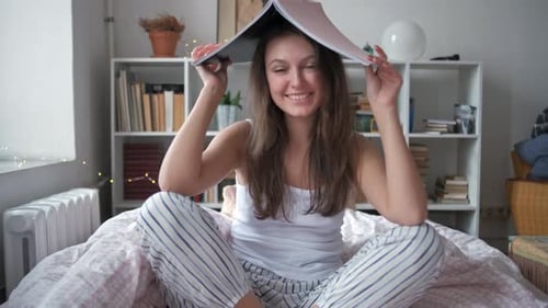 Woman with a Magazine Sitting on the Bed