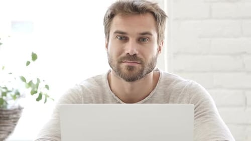 Young Adult Man Talking into Laptop Camera Indoors