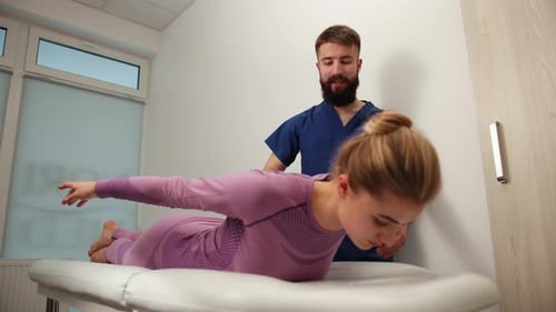 Chiropractor Adjusting Woman's Back in Clinic Exam Room
