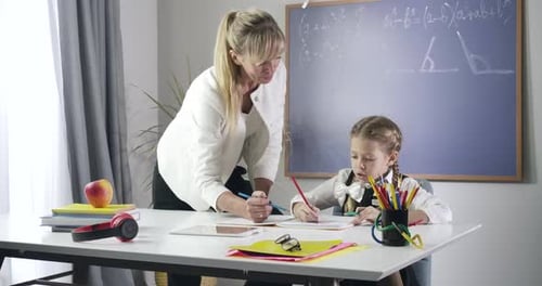 Teacher Helping Girl with Schoolwork in Classroom