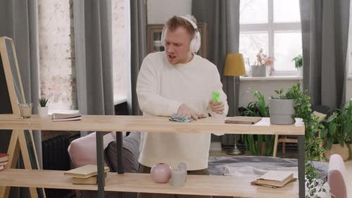 Man Dancing and Cleaning Shelves in Apartment