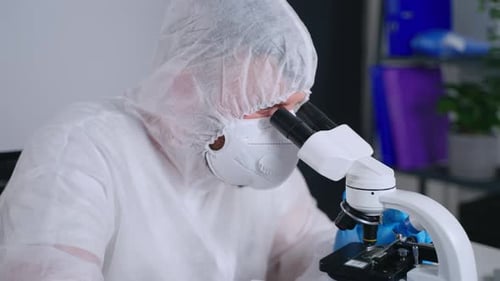 Scientist Examining Sample Through Microscope in Lab