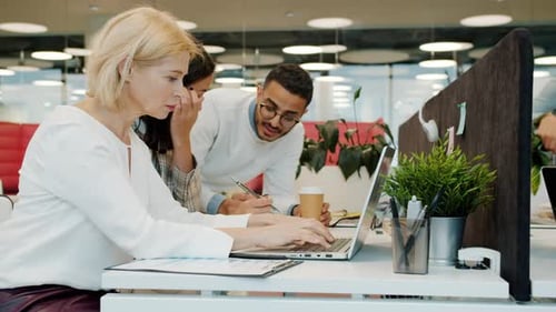Slow Motion of Colleagues Using Laptops and Talking in Shared Workspace Office