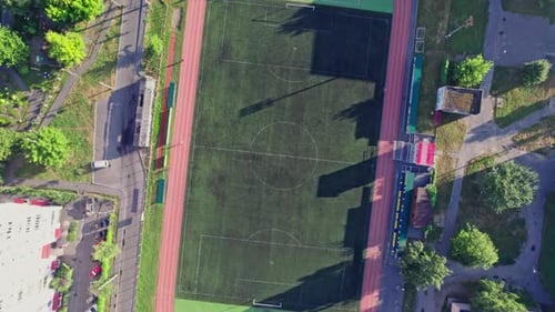 Buildings with Street in Small Town with Empty Football Soccer Field