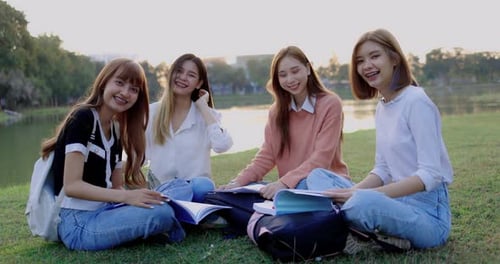 Grupo de amigas estudantes universitárias asiáticas estão sentadas juntas no parque.