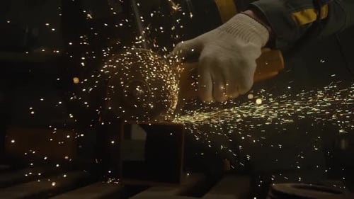 Gloved Hand Grinds Metal, Showering Sparks